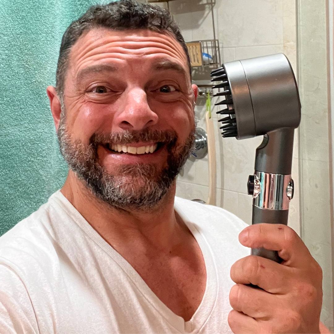 Happy male customer holding the FlowMist high-pressure filtered showerhead in his bathroom during a review photo.